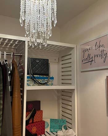 A walk-in closet with a chandelier shade hanging from the ceiling light 