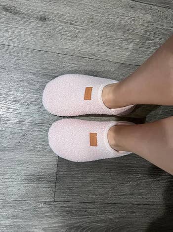 Reviewer wearing light textured slip-on slippers standing on a wooden floor