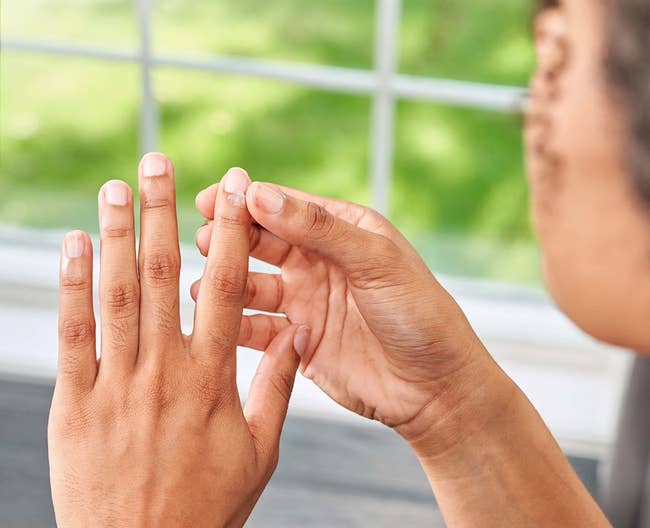 Person applying a skincare merchandise to their fingers by a window