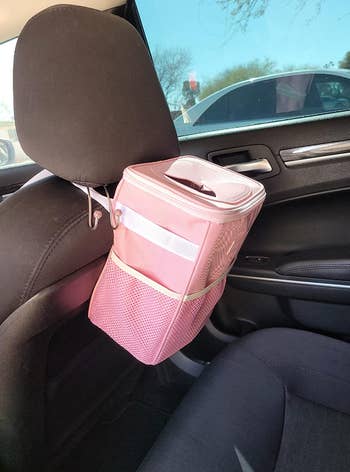 reviewer's pink car trash can strapped to the back of the passenger headrest