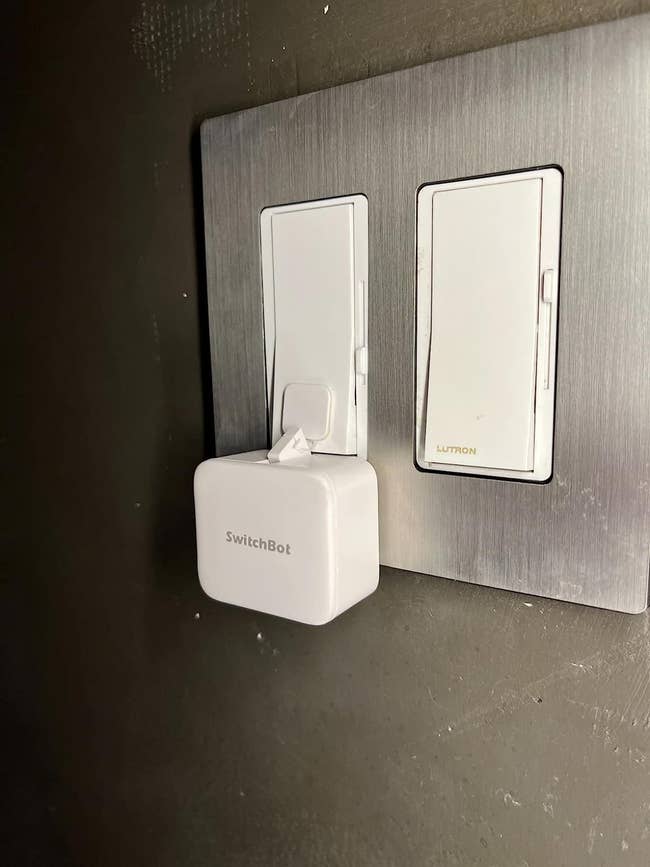 The reviewer's Switchbot mounted on a light switch.