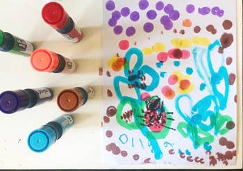 Child's artwork with paint bottles and colorful dots and scribbles on paper