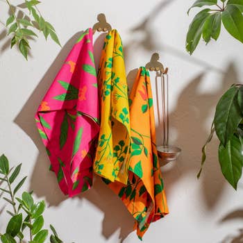 Vibrant floral-patterned towels successful  pinkish  and yellowish  bent  connected  hooks, surrounded by greenish  foliage. Perfect for adding a tropical interaction   to your bath  decor