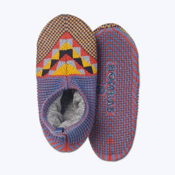 a pair of red, yellow, and blue patterned grippy slippers with a soft lining inside