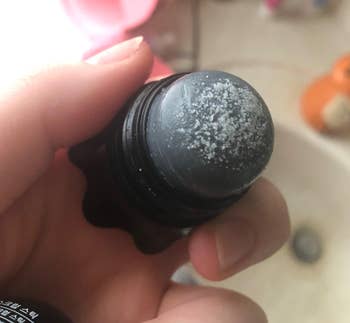 reviewer holding the remover with the cap off to show the salt on the top 