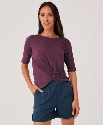Model wearing a purple tee with a twist design in front 