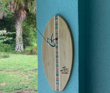 reviewer photo of the Tiki Toss game mounted to wall outside
