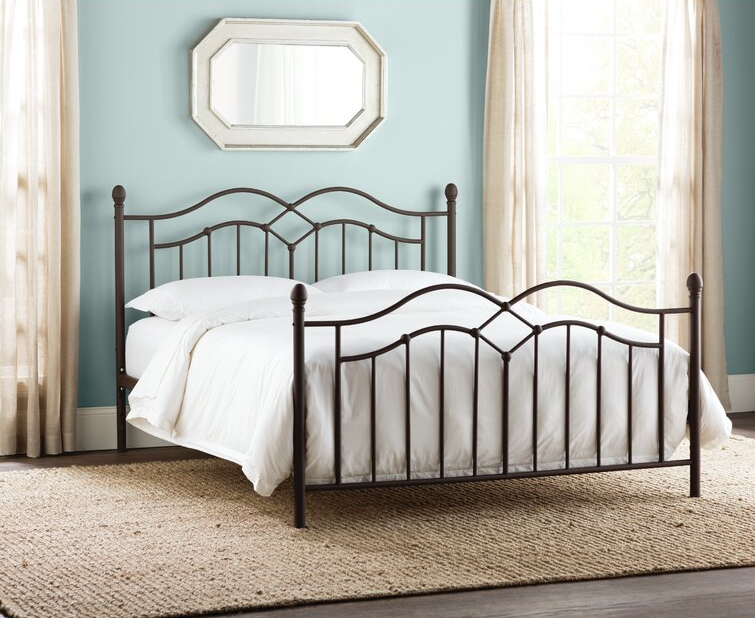 a black metal bed frame with a bed made up in white bedding on it