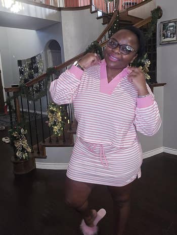 Person posing connected a staircase, wearing a striped casual formal with a v-neck and drawstring waist, accessorized with glasses and pinkish slippers