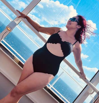 Person poses outdoors in a stylish cutout swimsuit, enjoying a scenic ocean view