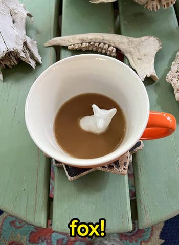 A coffee cup with an animal shape inside, surrounded by bones and natural items on a table. Word 