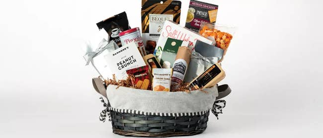 a woven gift basket filled with several, meats, cheeses, cookies, crackers, and nuts