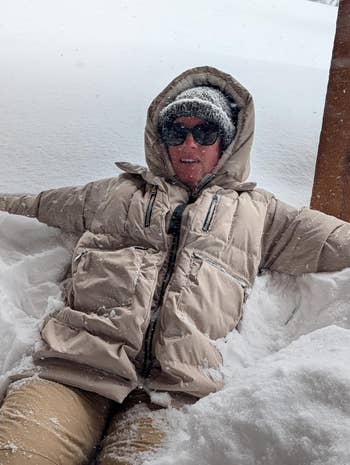 Person successful puffy wintertime coat, knit hat, and sunglasses sitting successful heavy snow, embodying cozy wintertime style