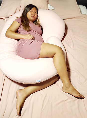 Reviewer using the pink pregnancy pillow