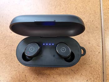 Reviewer showing open case with both earbuds in and showing off the lights so you know how charged they are