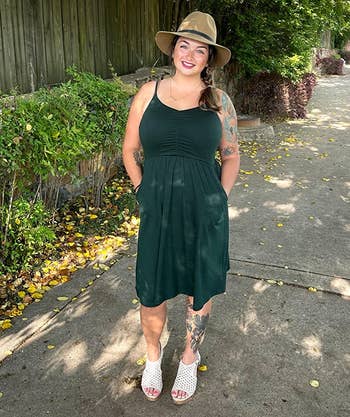 reviewer wearing the green dress with a hat and heeled sandals