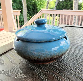 a reviewer photo of the ashtray in blue sitting on a table outside 