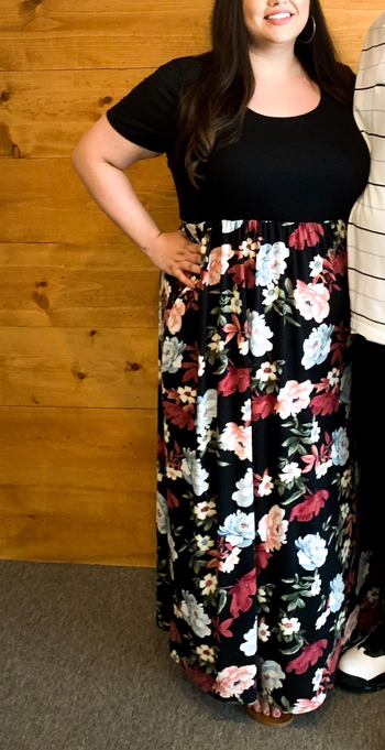 reviewer wearing the dress in black with a peony pattern on the bottom