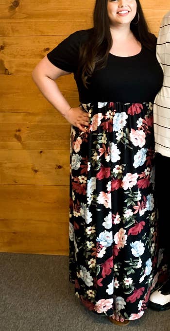 reviewer wearing the dress in black with a peony pattern on the bottom