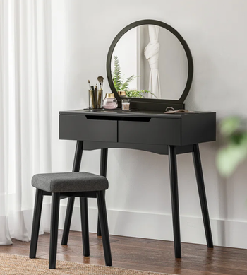 lifestyle photo of black vanity with circular mirror, matching stool