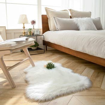 the faux sheepskin rug next to chair beside bed