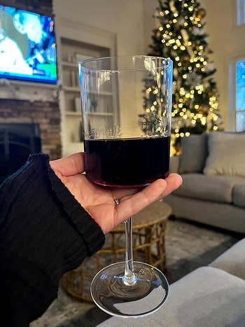 hand holding a glass with red wine in it