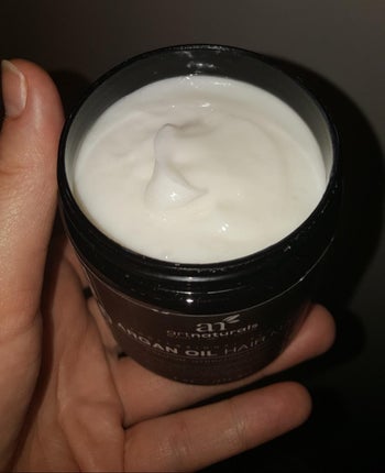 reviewer holding up open container of the hair mask