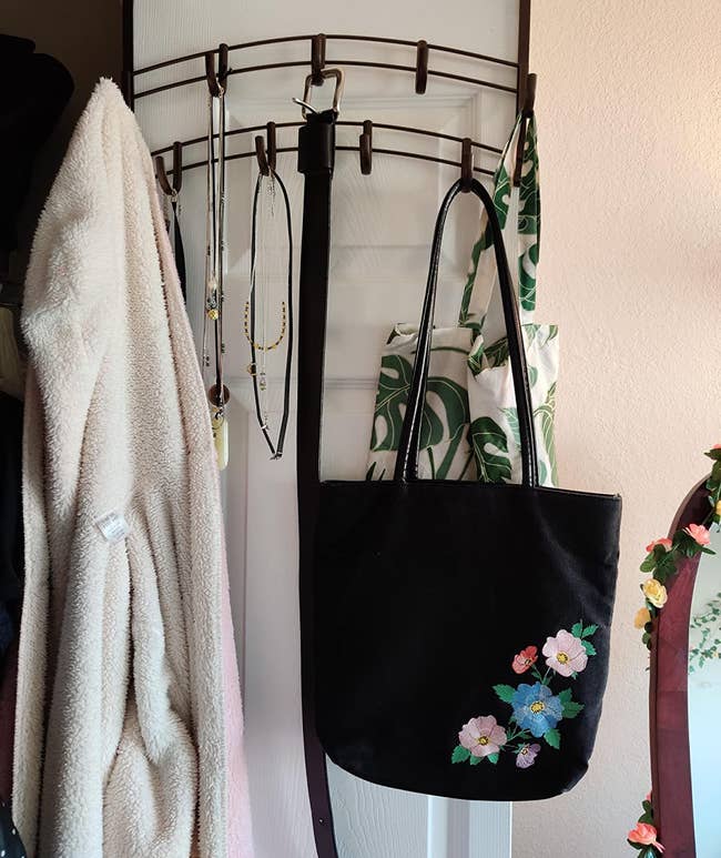 Reviewer photo of the rack over a door holding a purse, jacket, and necklaces