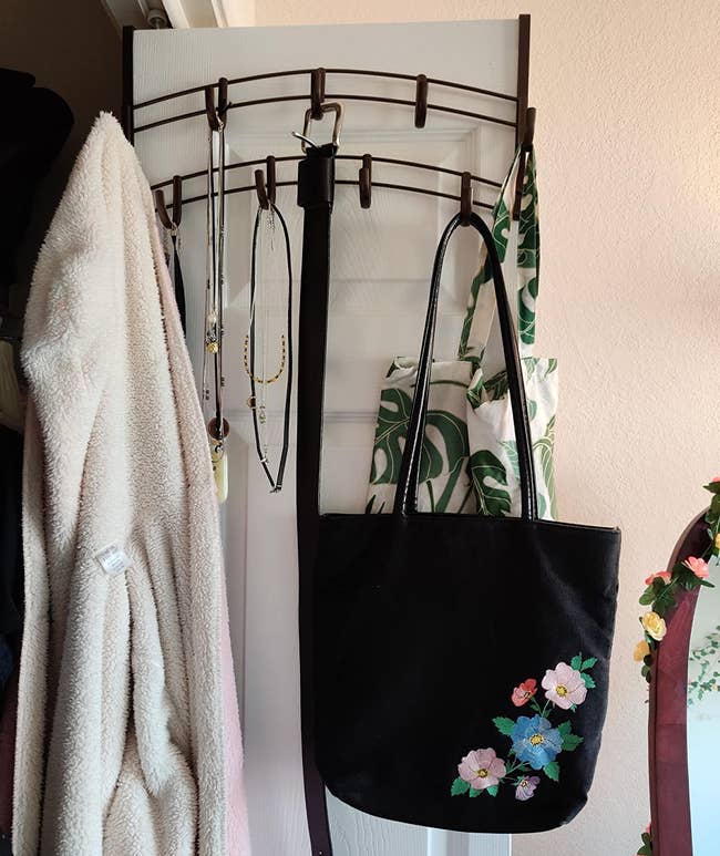 Reviewer photo of the rack over a door holding a purse, jacket, and necklaces