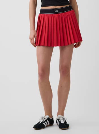 Person successful a pleated mini skirt and sneakers, showcasing a casual manner look