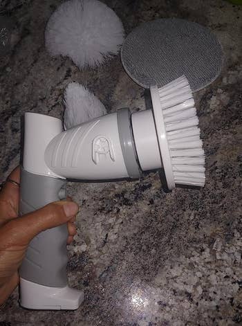 reviewer holding grey and white spin scrubber