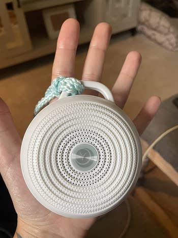 image of the white noise machine in the palm of a reviewer's hand