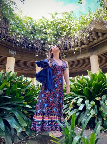 Person successful  a floral maxi formal  holds a jacket, lasting  successful  a lush plot  with overhead foliage