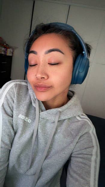 Person with headphones wearing a casual hoodie, eyes closed, appears relaxed. Suitable for a buying nonfiction connected cozy, stylish homewear