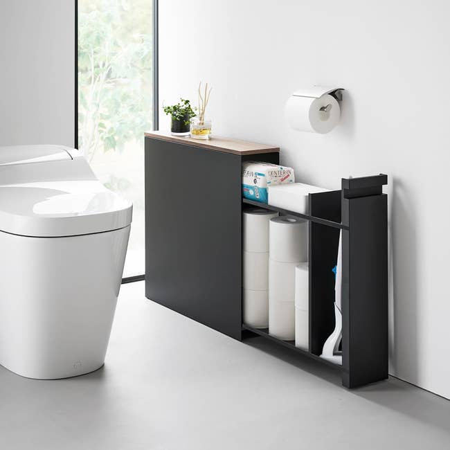 Modern bath retention furniture with sliding shelves holding toilet insubstantial and cleaning supplies adjacent to a toilet