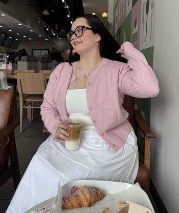 different reviewer sitting successful a cafe wearing the cardigan successful pink