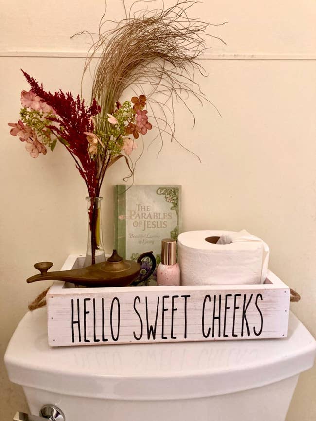 box that says hello sweet cheeks on top of toilet tank