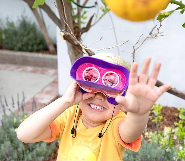 Child plays with educational binocular toy outdoors 