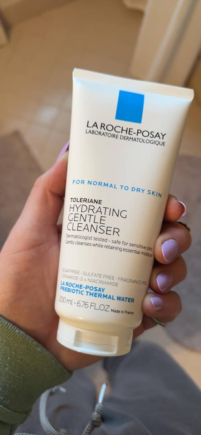 A reviewer's Hand holding La Roche-Posay Toleriane Hydrating Gentle Cleanser for mean   to adust  skin; harmless  for delicate  skin, 200 ml bottle