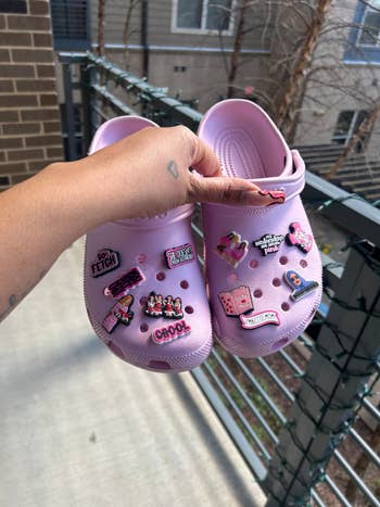 me holding my pink Crocs with Mean Girls charms on them