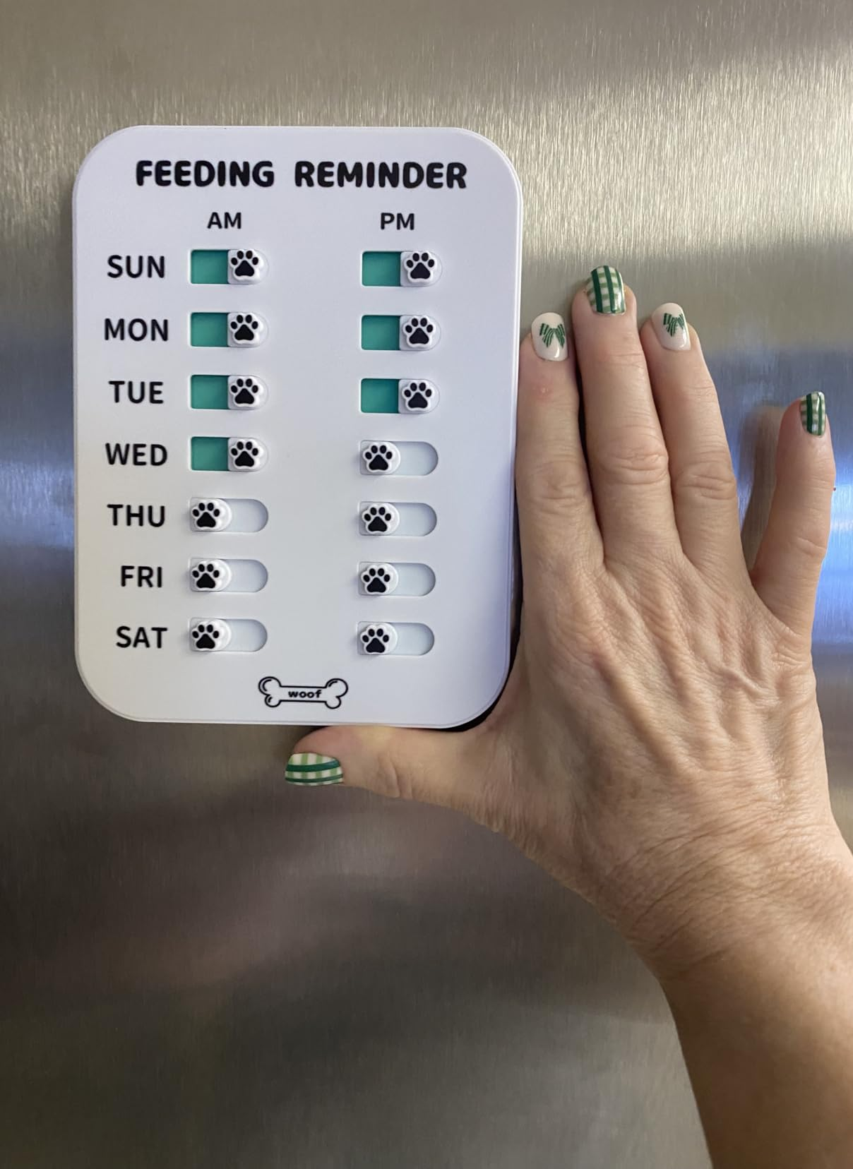 Hand showing a play   favored  feeding reminder with checkboxes for AM and PM feedings, indicating completed days with paw prints