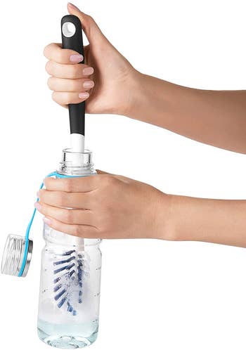 hands using large brush inside a bottle