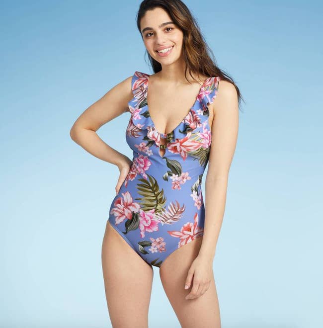 a model in a light blue one-piece bathing suit with tropical pink florals on it