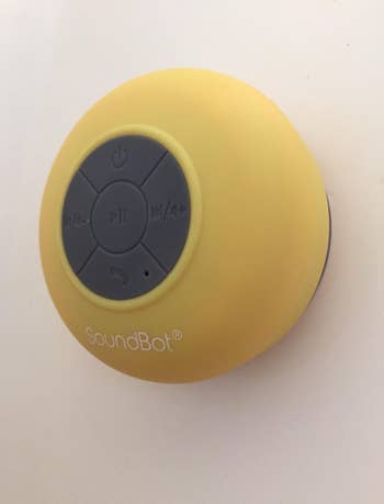 a reviewer photo of the speaker in yellow mounted on. a shower wall 