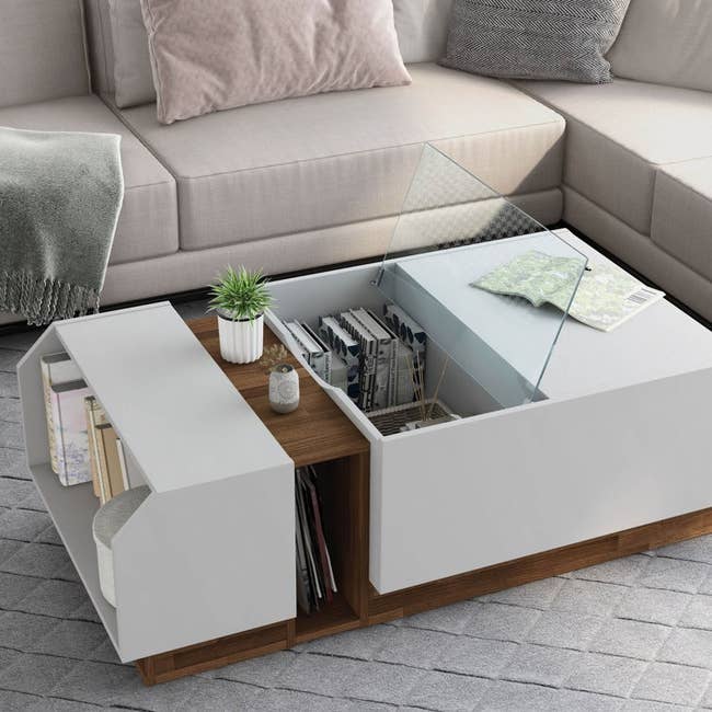 a coffee table with a side shelf  and inner compartment with an open glass lid 