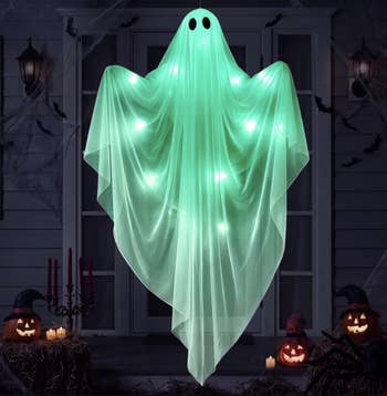 Floating shade decoration with glowing lights, surrounded by Halloween pumpkins and candles connected a porch