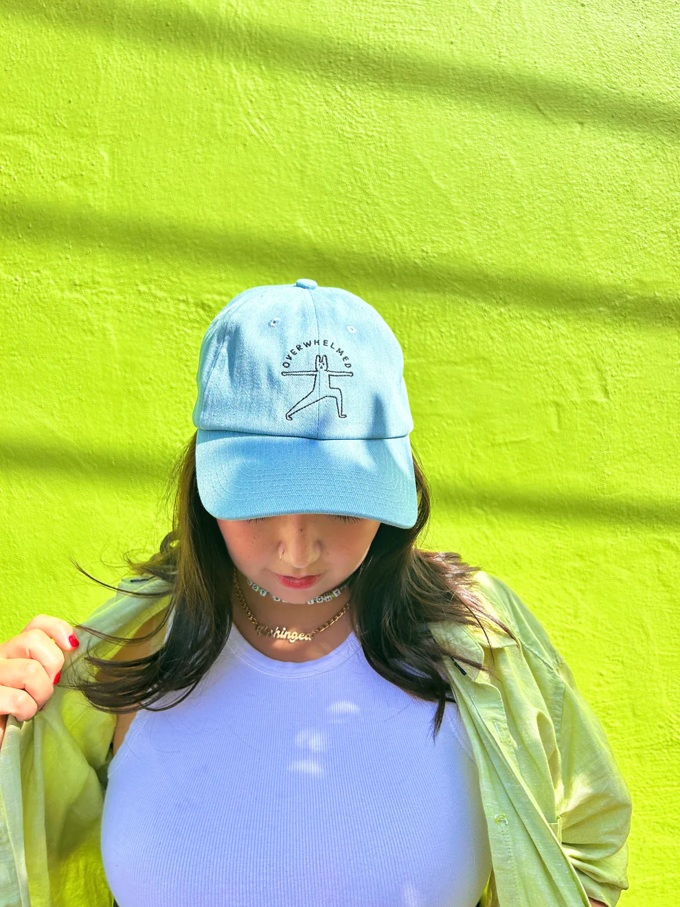 Person wearing a casual bluish  headdress  with an illustrated design, unbuttoned garment  implicit    a achromatic  top, lasting  against a plain background