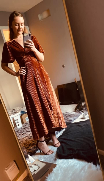 reviewer mirror selfie wearing the dress in orange velvet