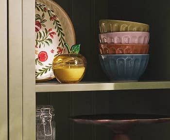 Kitchen support with neatly stacked bowls, a decorative plate, containers, and woody utensils. A cozy, organized mounting for location and room shopping
