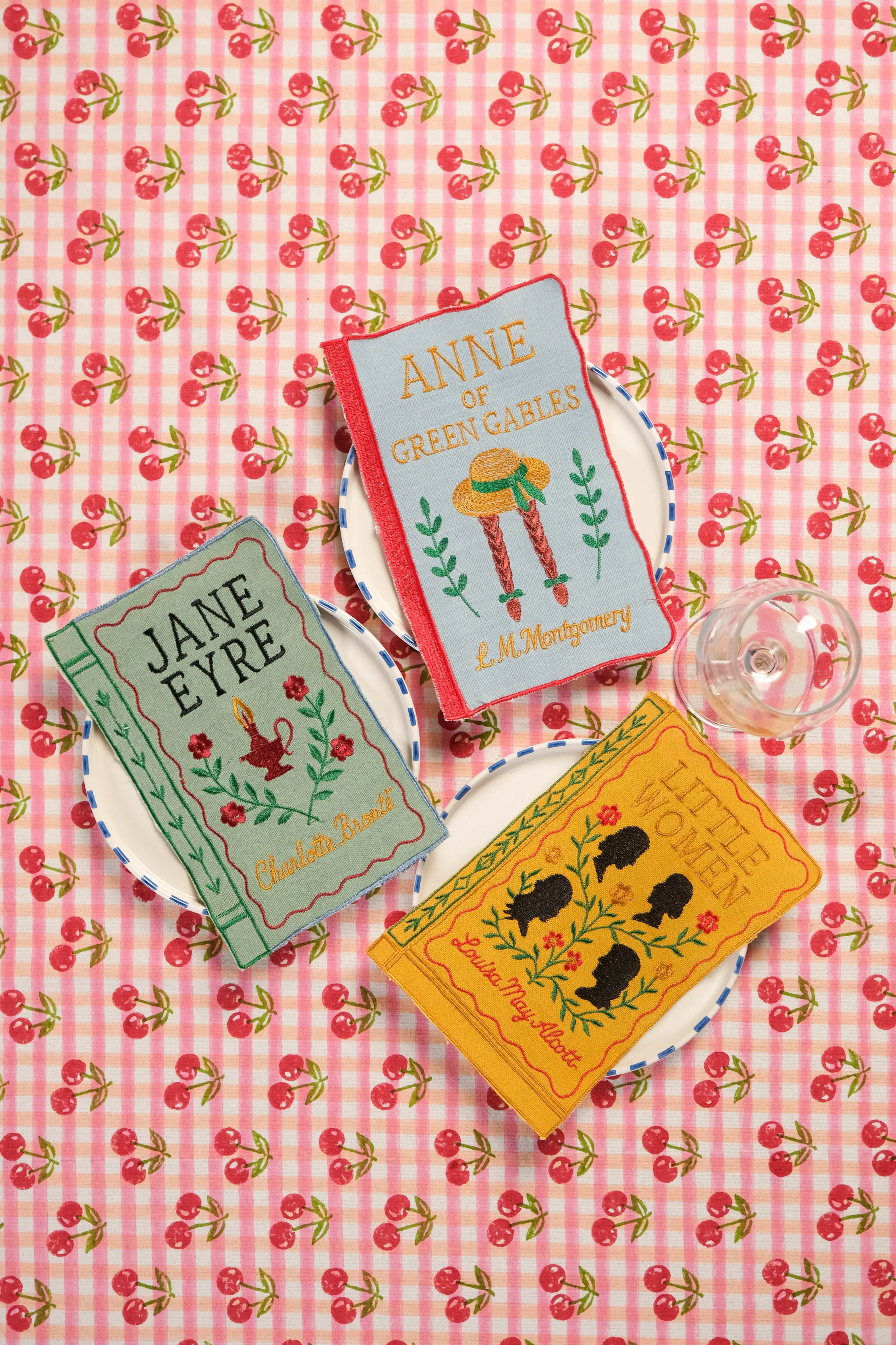 Three embroidered book-themed clutches labeled arsenic  